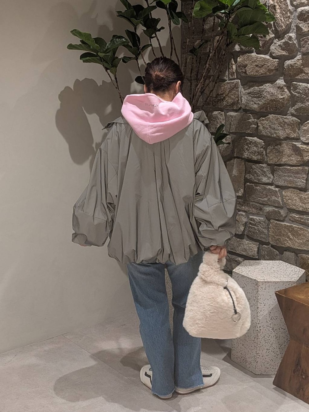 ベージュ系のハンドバッグ、ブルー系のデニムパンツ、ホワイト系のスニーカーを着用したレディースの秋コーディネートの3枚目の写真