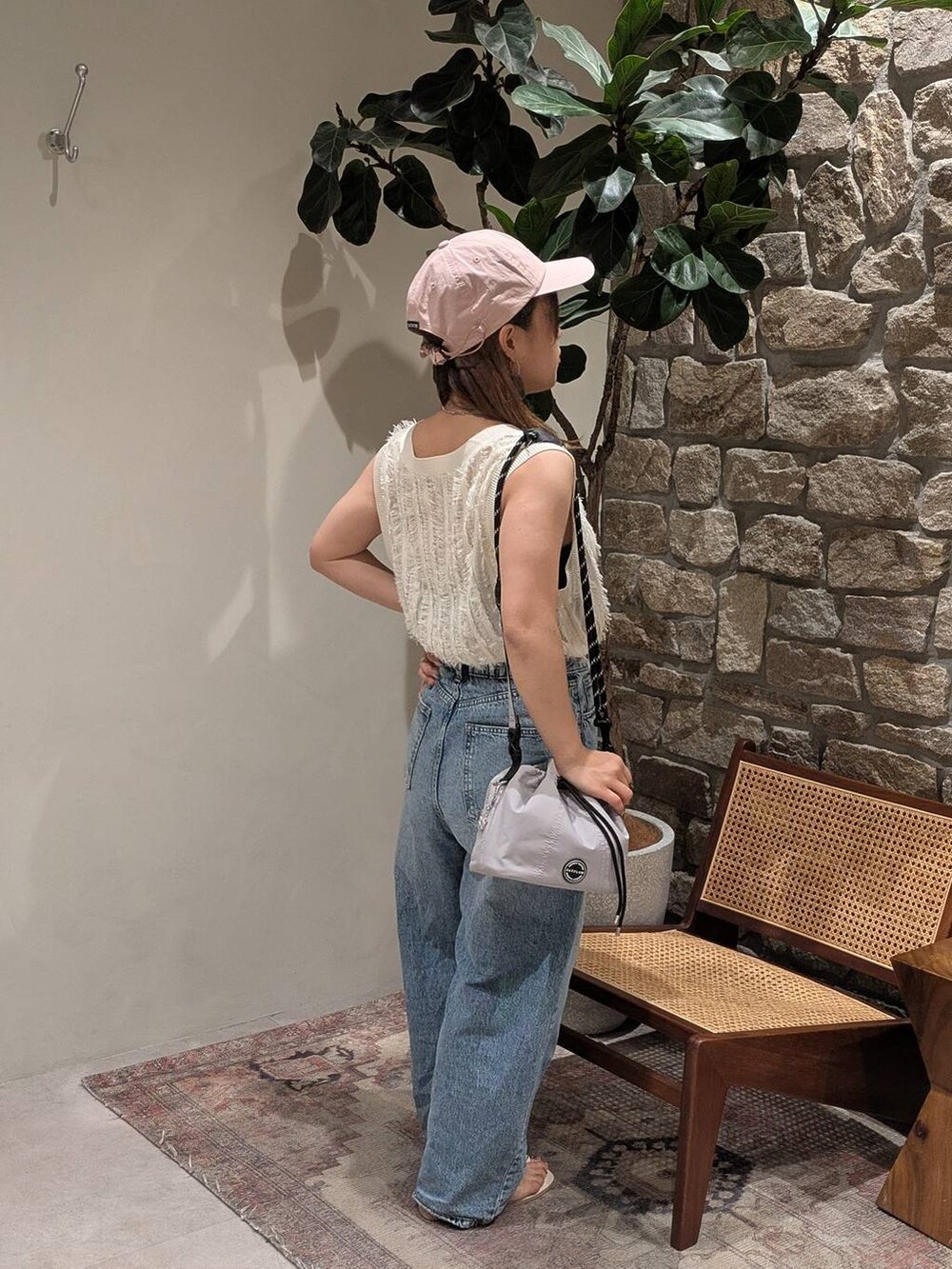 ブルー系のデニムパンツ、グレー系のショルダーバッグ、ホワイト系のサンダルを着用したレディースの夏コーディネートの3枚目の写真