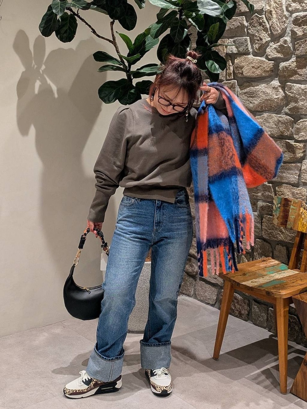 ブラック系のハンドバッグ、オレンジ系のマフラーを着用したレディースの冬コーディネートの2枚目の写真