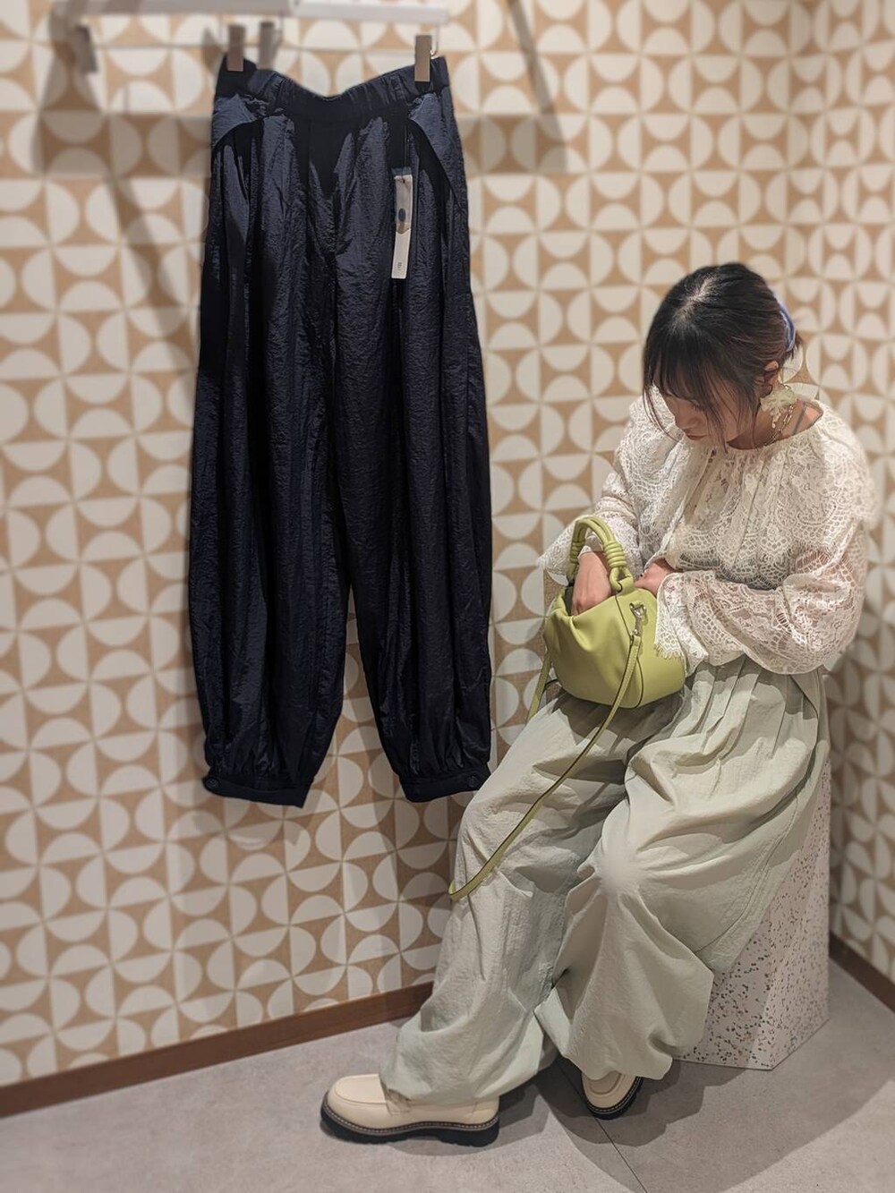 グリーン系のハンドバッグ、ホワイト系のローファー、グレー系のその他パンツを着用したレディースの冬コーディネートの6枚目の写真