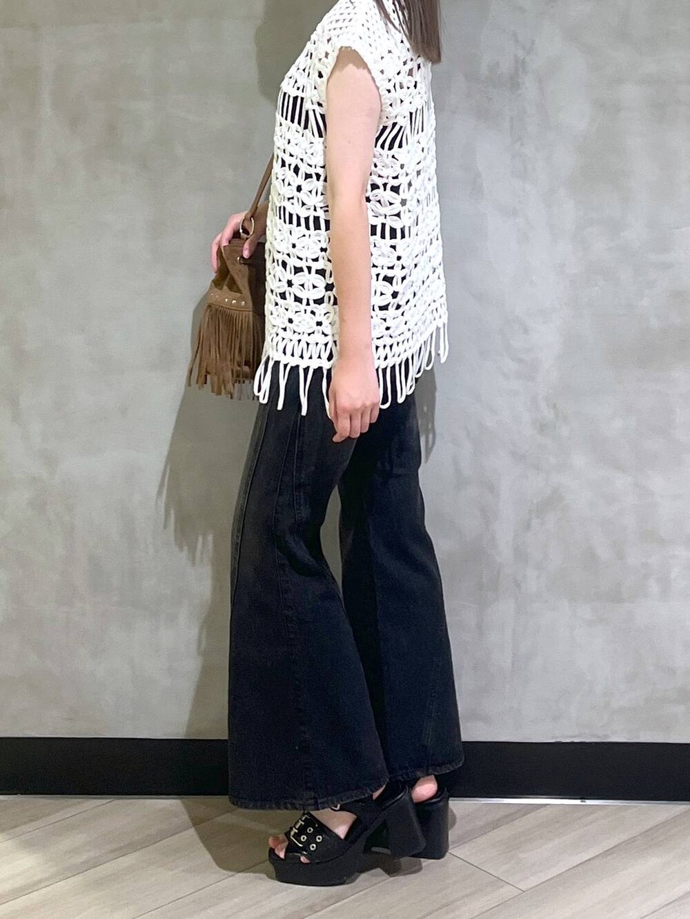 ブラック系のブーツ、ブラック系のデニムパンツ、ホワイト系のベストを着用したレディースの夏コーディネートの4枚目の写真