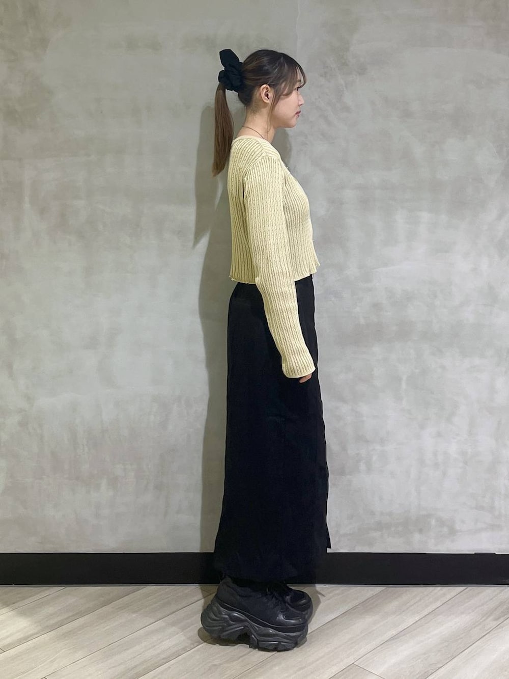 ブラック系のブーツ、イエロー系のカーディガン/ボレロ、ブラック系のスカートを着用したレディースの秋コーディネートの7枚目の写真