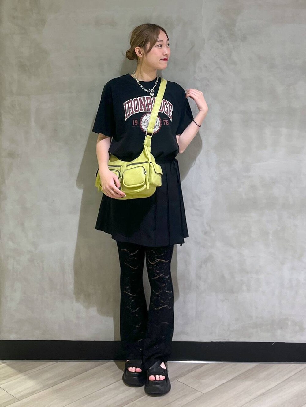 ブラック系のサンダル、ブラック系のスカート、グリーン系のショルダーバッグを着用したレディースの春コーディネートの3枚目の写真