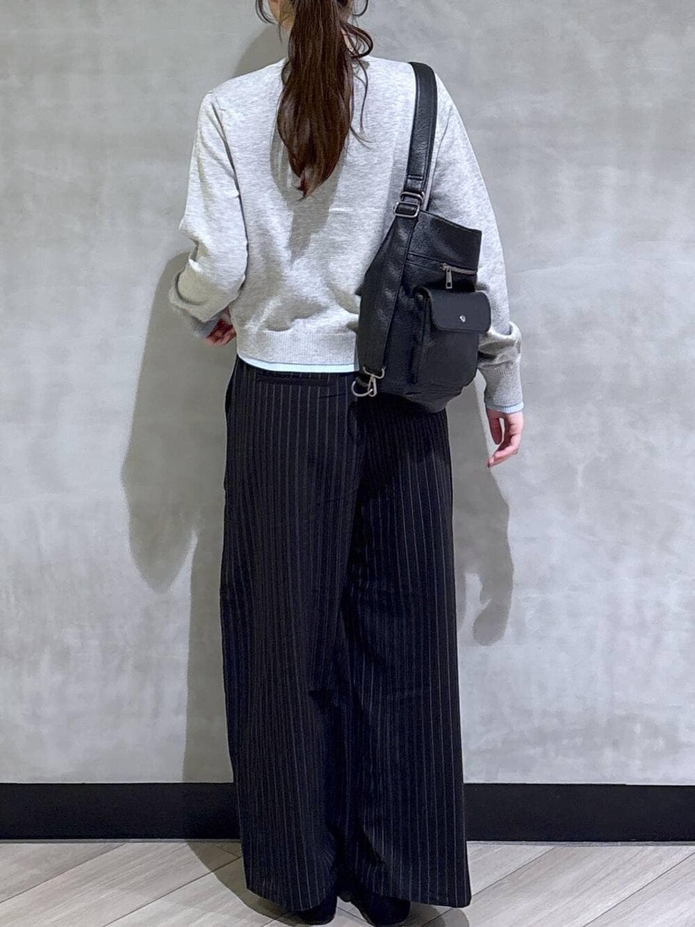 ブラック系のスラックス、グレー系のカーディガン/ボレロ、ブラック系のモカシン/デッキシューズを着用したレディースの春コーディネートの6枚目の写真