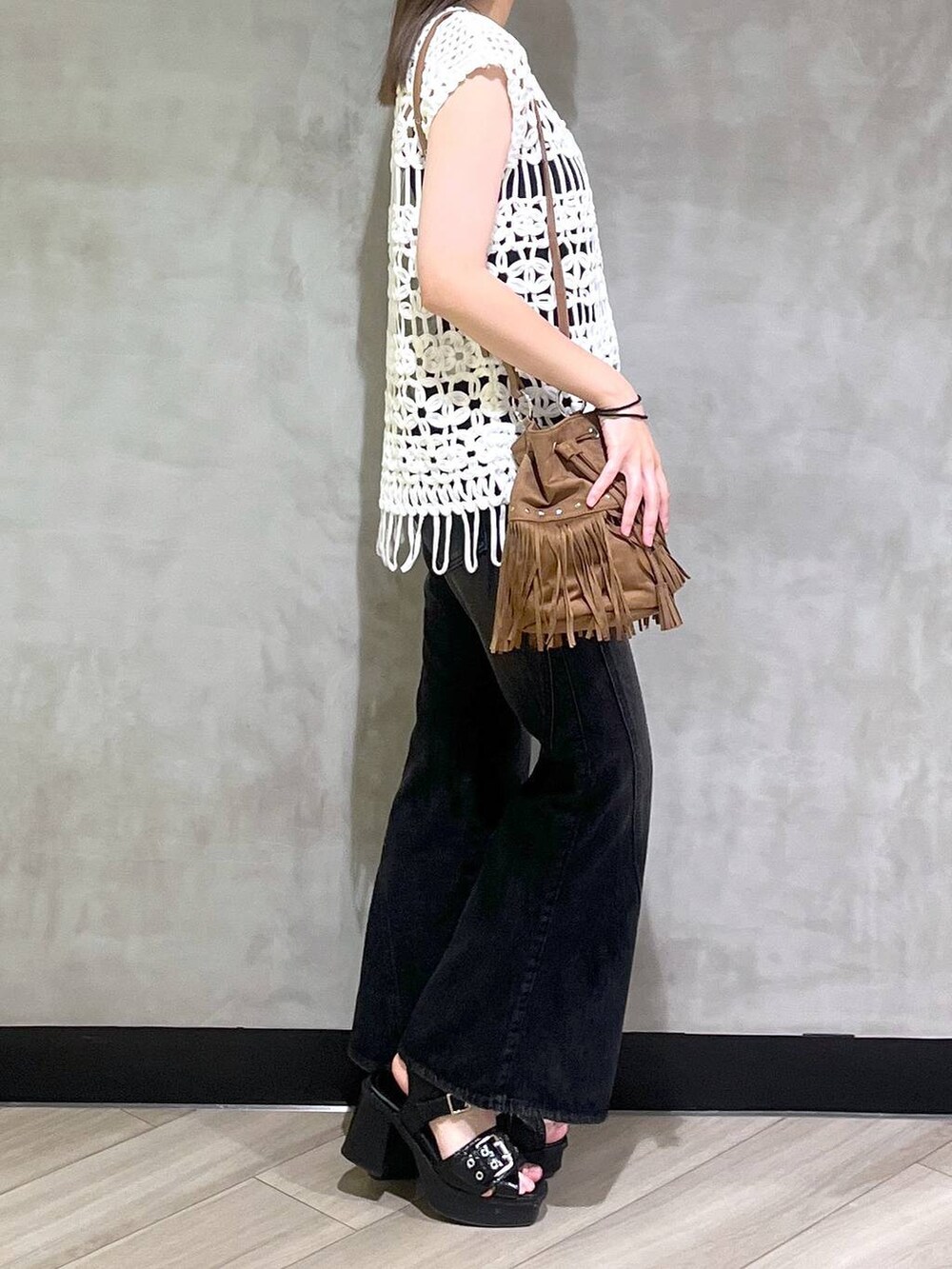 ブラック系のブーツ、ブラック系のデニムパンツ、ホワイト系のベストを着用したレディースの夏コーディネートの8枚目の写真