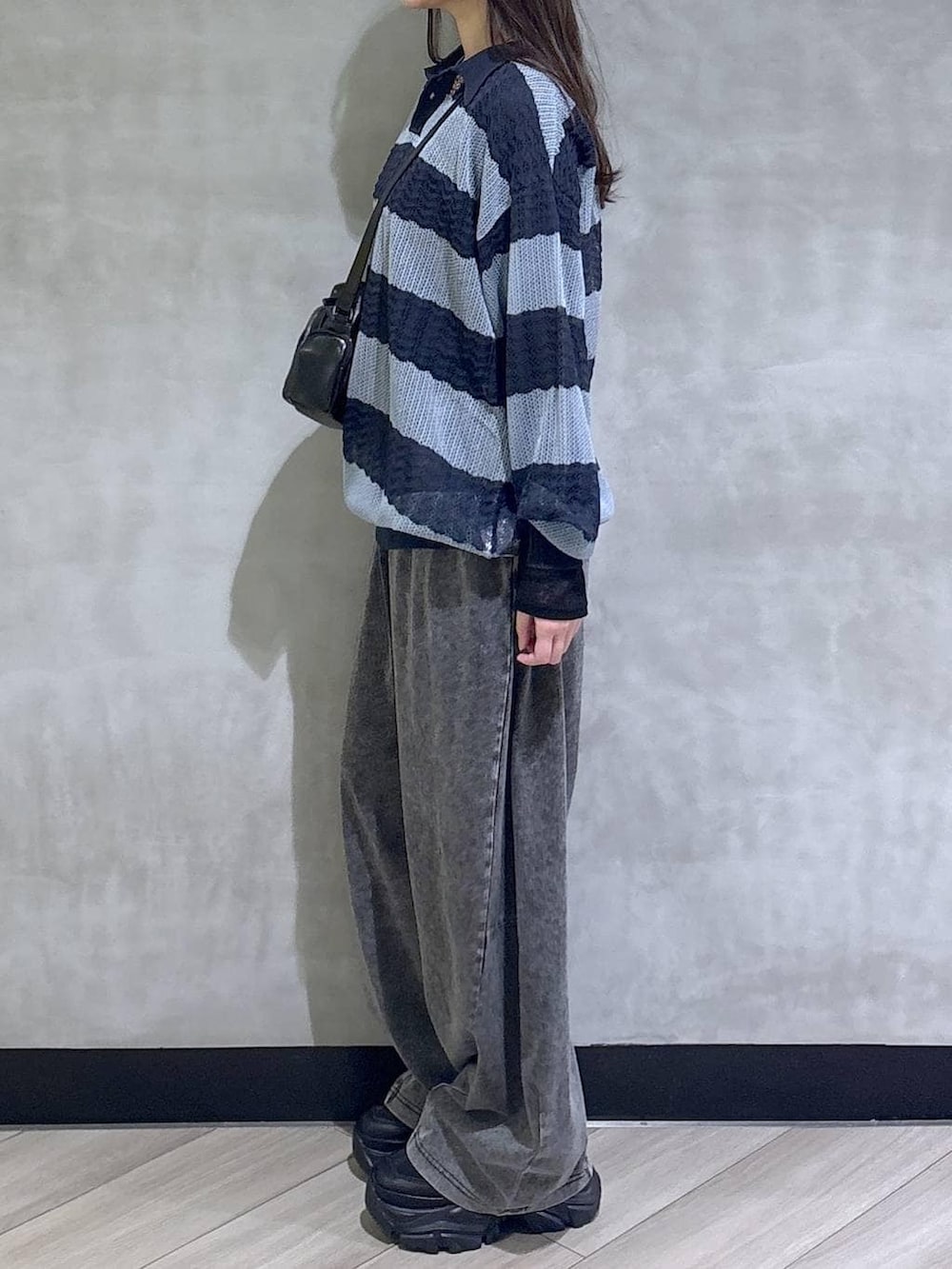 ブラック系のスニーカー、ブラック系のデニムパンツ、ブルー系のポロシャツを着用したレディースの春コーディネートの4枚目の写真