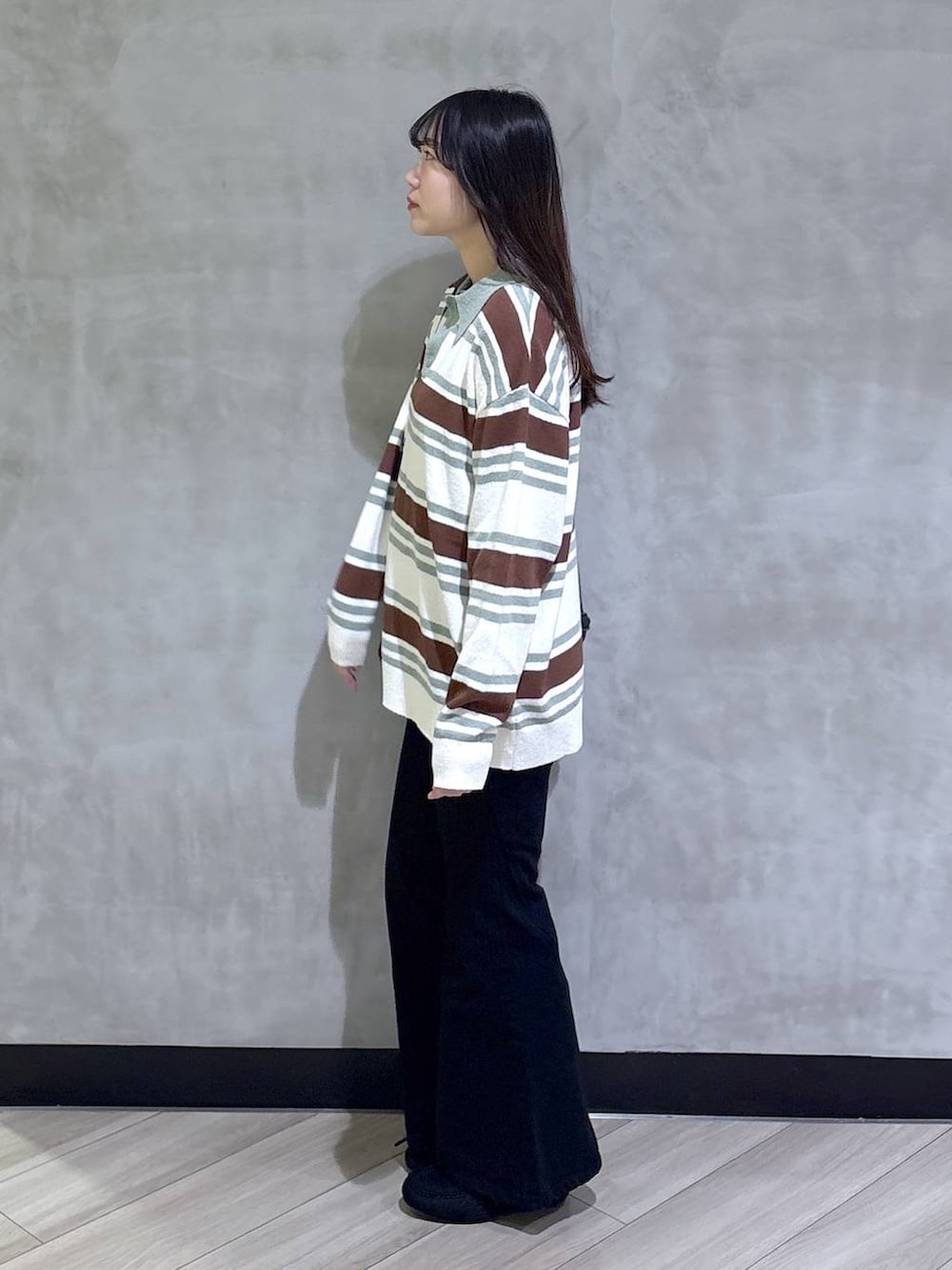 ブラック系のデニムパンツ、ブラック系のモカシン/デッキシューズ、グリーン系のニット/セーターを着用したレディースの春コーディネートの3枚目の写真