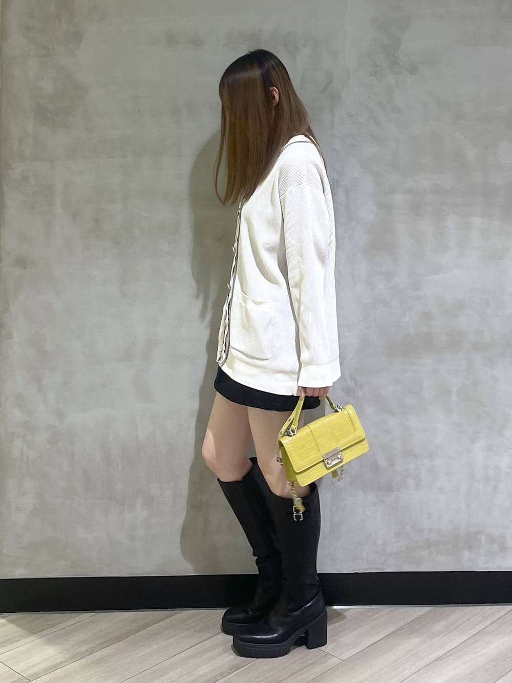 ブラック系のブーツ、ブラック系のスカート、ホワイト系のカーディガン/ボレロを着用したレディースの秋コーディネートの3枚目の写真