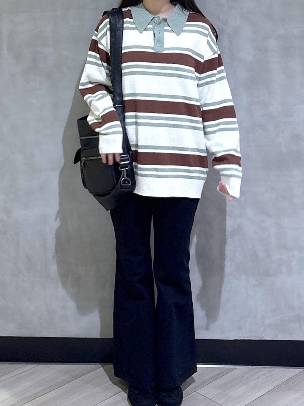 ブラック系のデニムパンツ、ブラック系のモカシン/デッキシューズ、グリーン系のニット/セーターを着用したレディースの春コーディネートの2枚目の写真