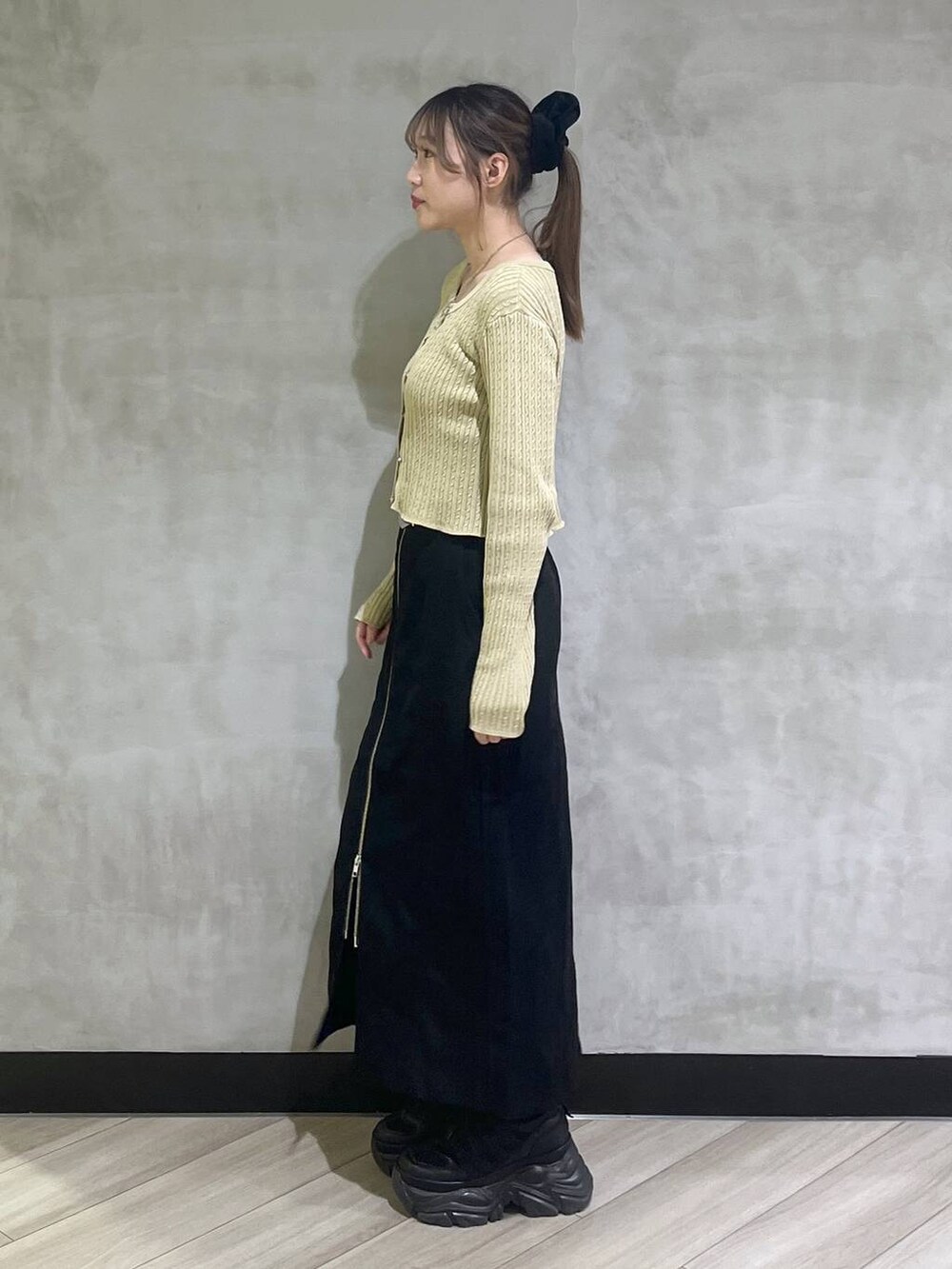 ブラック系のブーツ、イエロー系のカーディガン/ボレロ、ブラック系のスカートを着用したレディースの秋コーディネートの3枚目の写真