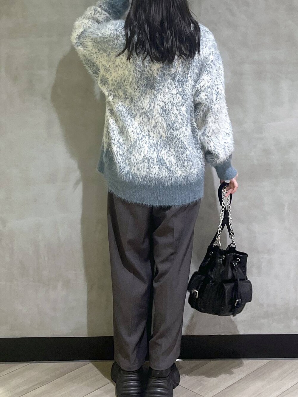 ブラック系のスニーカー、ブルー系のニット/セーター、グレー系のスラックスを着用したレディースの秋コーディネートの6枚目の写真