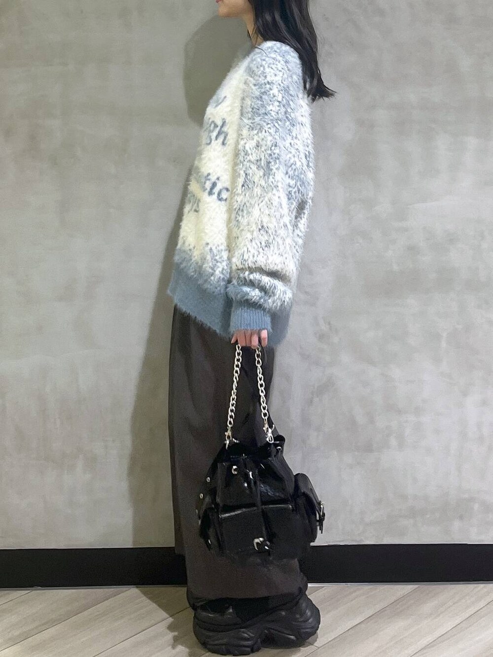 ブラック系のスニーカー、ブルー系のニット/セーター、グレー系のスラックスを着用したレディースの秋コーディネートの4枚目の写真