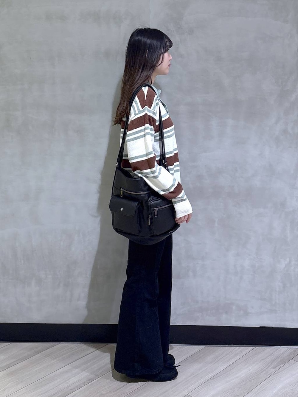 ブラック系のデニムパンツ、ブラック系のモカシン/デッキシューズ、グリーン系のニット/セーターを着用したレディースの春コーディネートの6枚目の写真