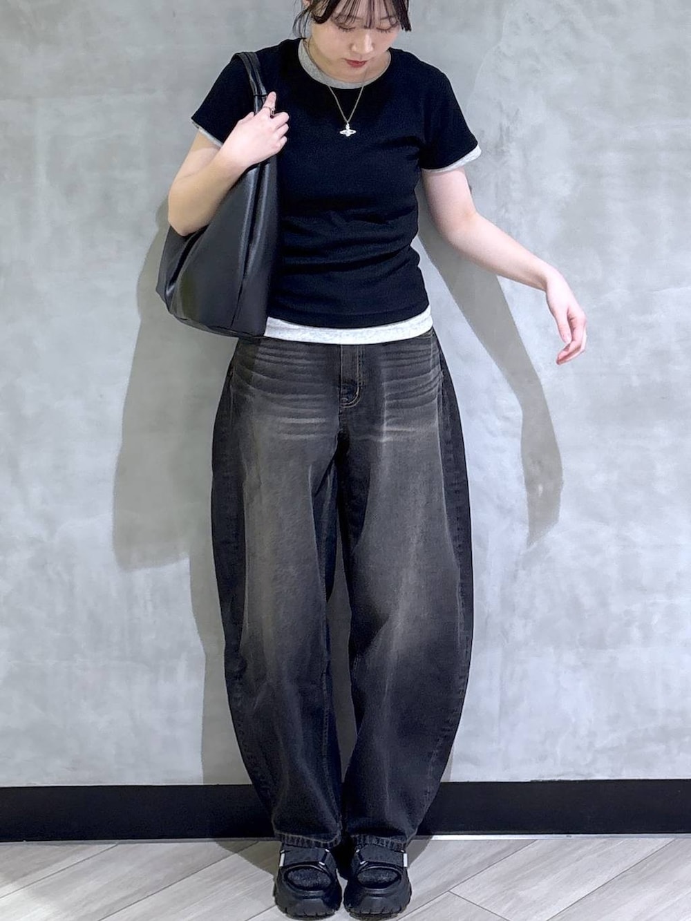 ブラック系のデニムパンツ、ブラック系のサンダル、ホワイト系のTシャツ/カットソーを着用したレディースの春コーディネートの2枚目の写真