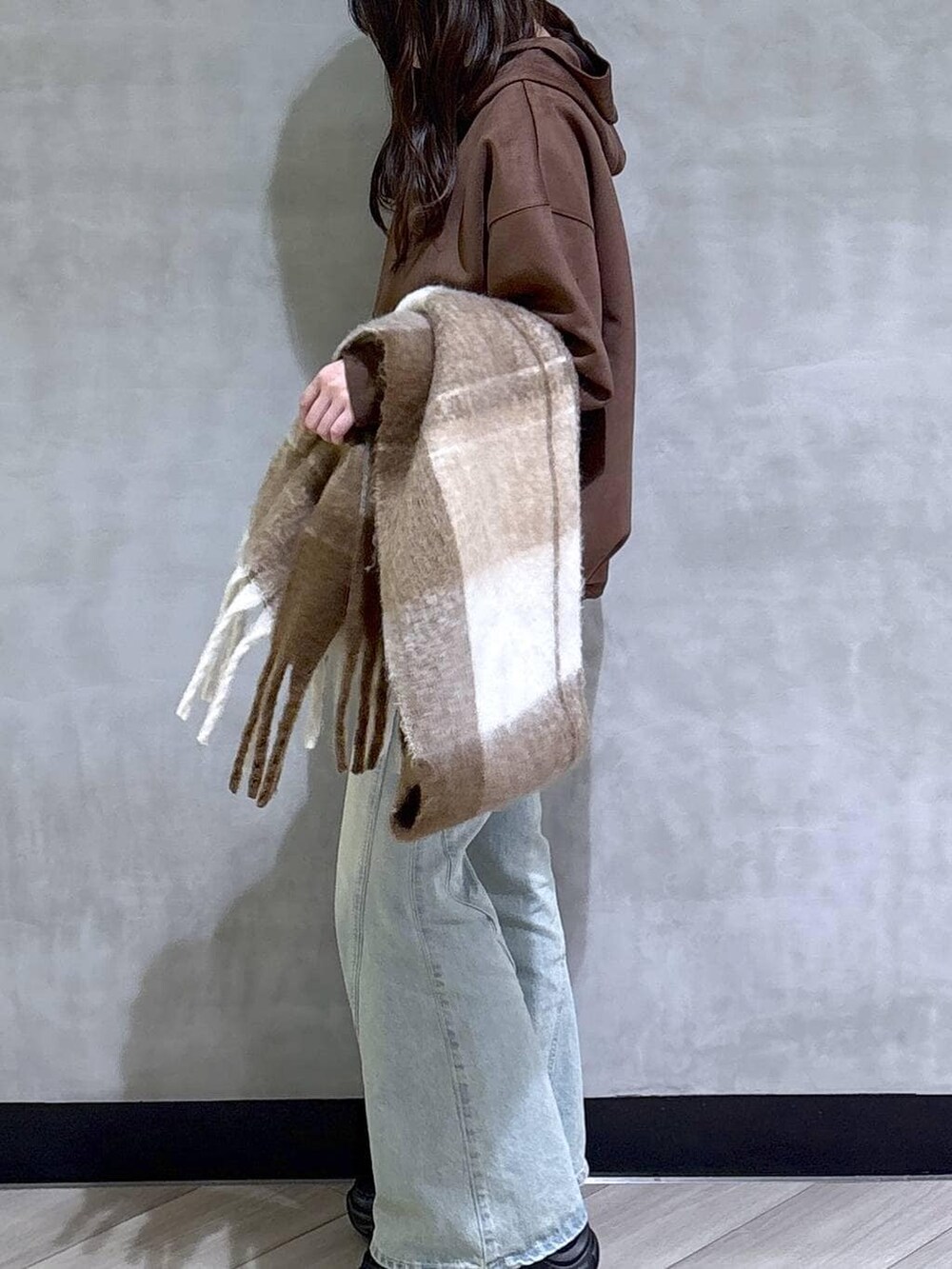 ブルー系のデニムパンツ、ブラック系のパーカー、ブラック系のローファーを着用したレディースの冬コーディネートの4枚目の写真