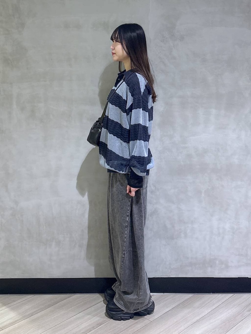 ブラック系のスニーカー、ブラック系のデニムパンツ、ブルー系のポロシャツを着用したレディースの春コーディネートの3枚目の写真