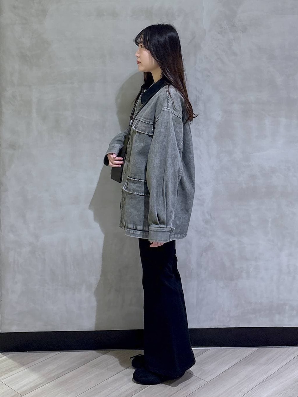ブラック系のデニムパンツ、ブラック系のモカシン/デッキシューズ、グリーン系のニット/セーターを着用したレディースの春コーディネートの3枚目の写真