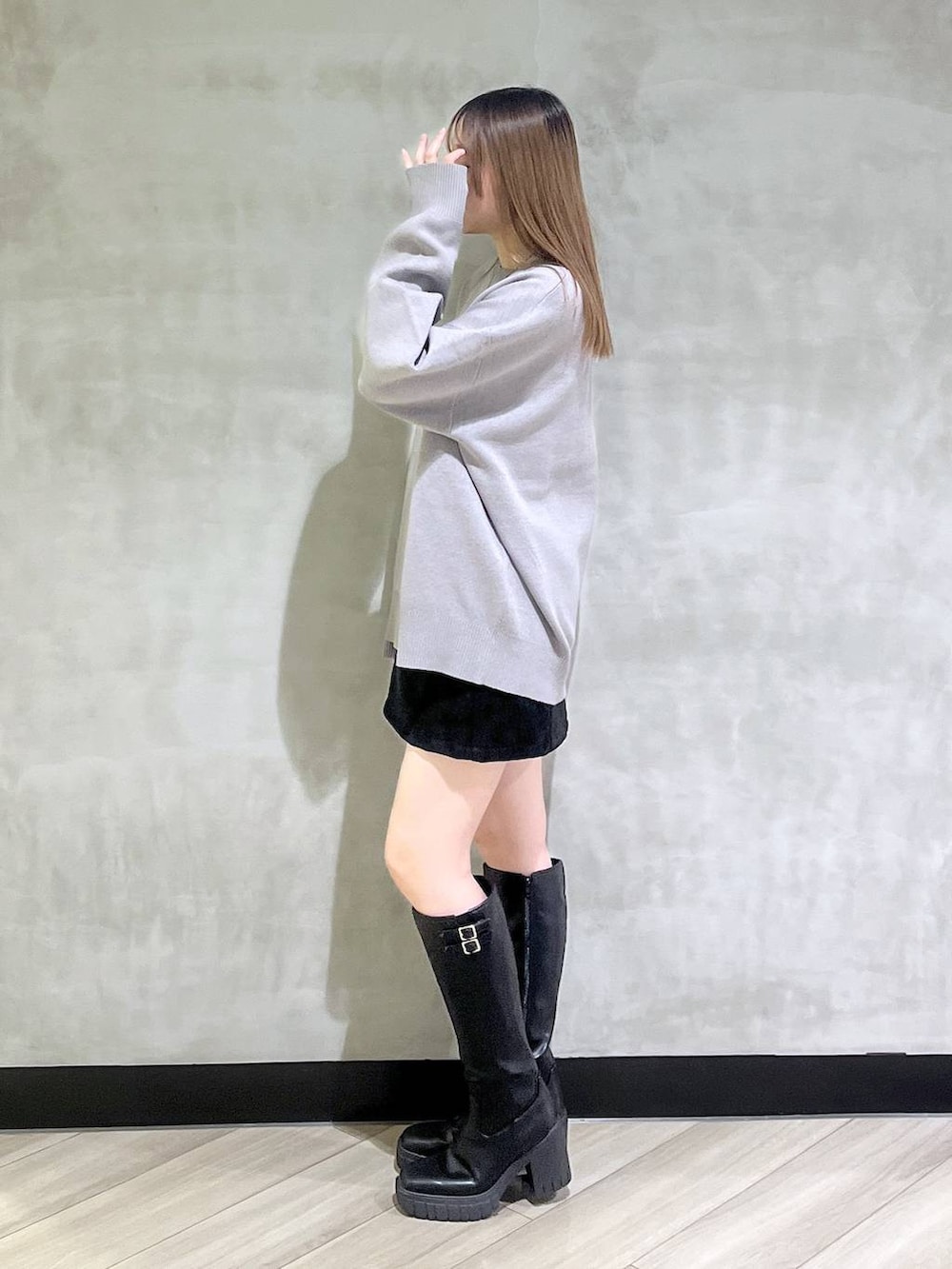 ブラック系のブーツ、ブラック系のスカート、グレー系のニット/セーターを着用したレディースの秋コーディネートの4枚目の写真