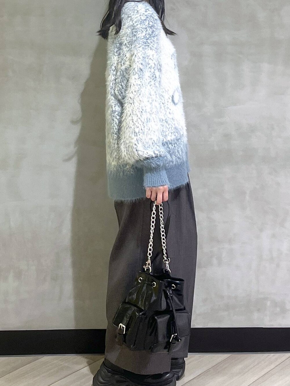 ブラック系のスニーカー、ブルー系のニット/セーター、グレー系のスラックスを着用したレディースの秋コーディネートの8枚目の写真