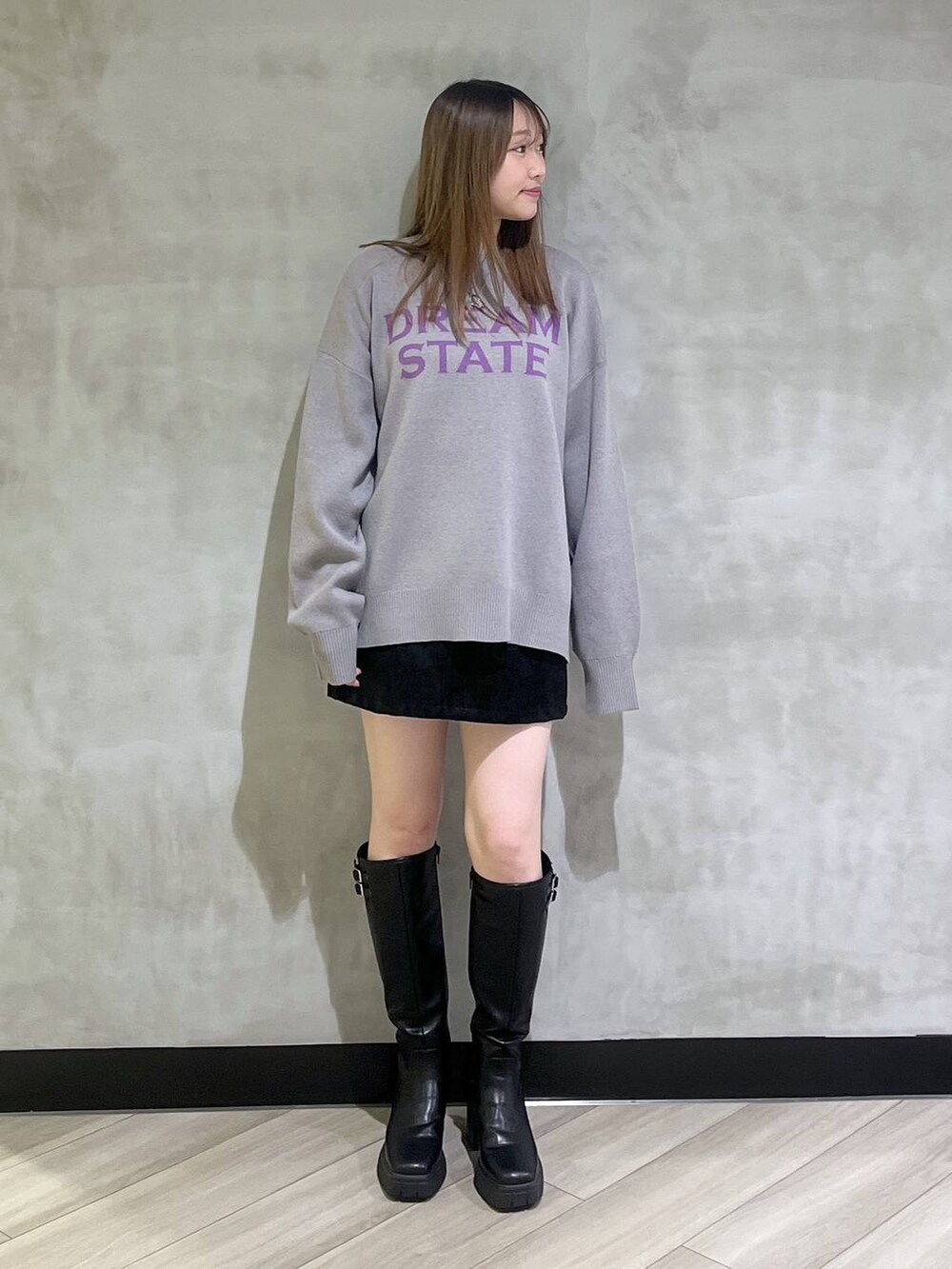 ブラック系のブーツ、ブラック系のスカート、グレー系のニット/セーターを着用したレディースの秋コーディネートの2枚目の写真