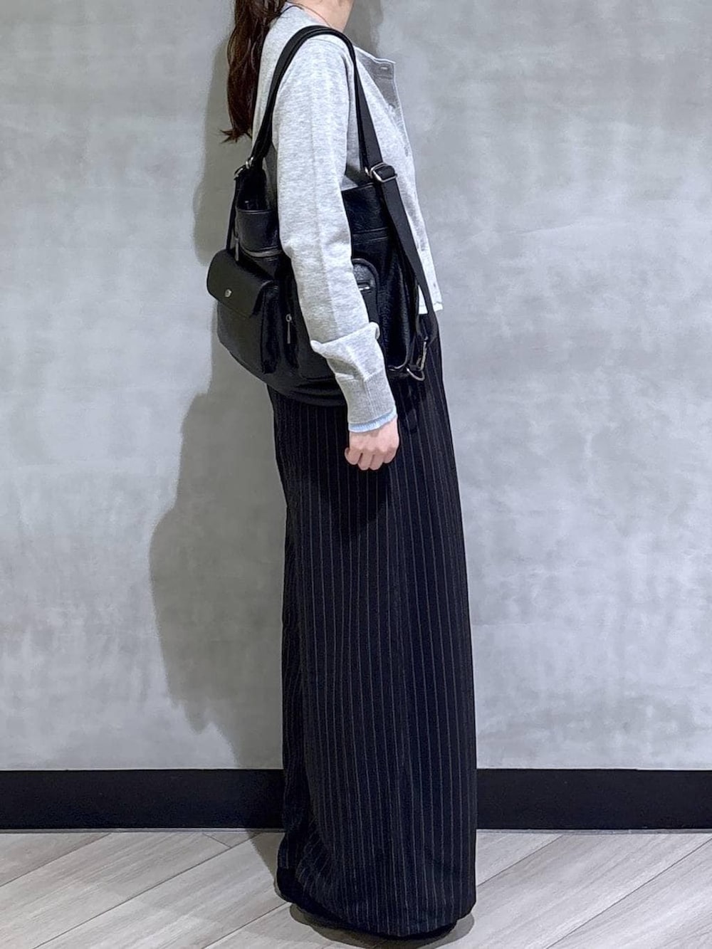 ブラック系のスラックス、グレー系のカーディガン/ボレロ、ブラック系のモカシン/デッキシューズを着用したレディースの春コーディネートの4枚目の写真