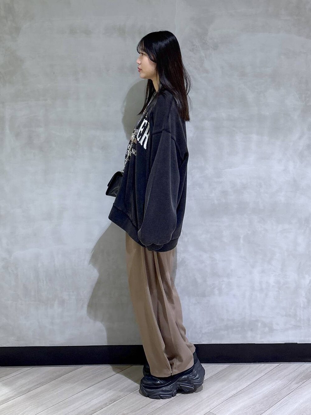 ブラック系のブーツ、グレー系のスウェット、ベージュ系のスラックスを着用したレディースの秋コーディネートの3枚目の写真