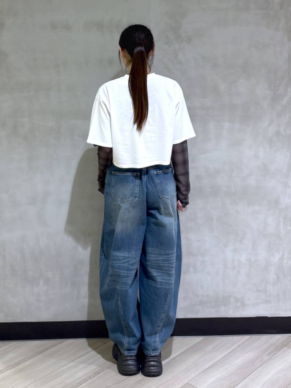 ブラック系のスニーカー、ホワイト系のTシャツ/カットソー、ブルー系のデニムパンツを着用したレディースの春コーディネートの5枚目の写真