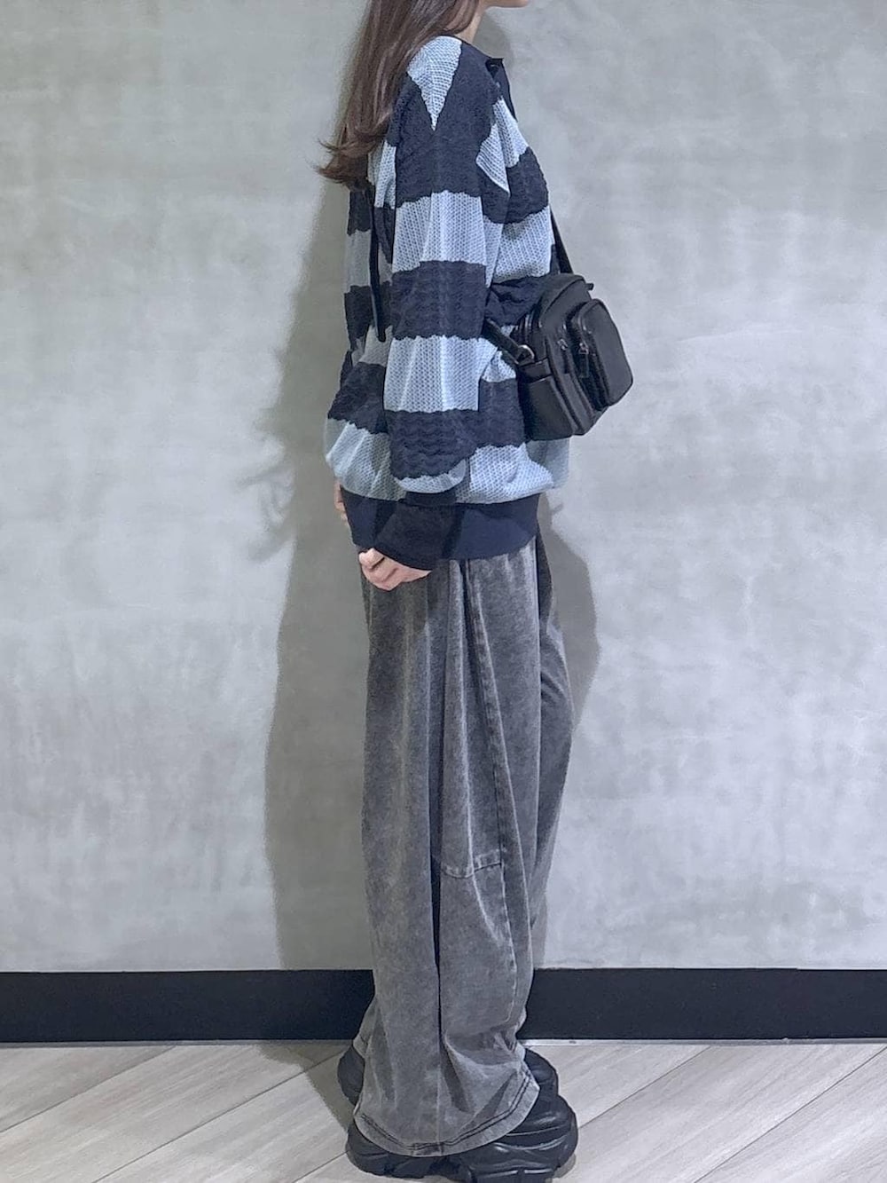 ブラック系のスニーカー、ブラック系のデニムパンツ、ブルー系のポロシャツを着用したレディースの春コーディネートの7枚目の写真