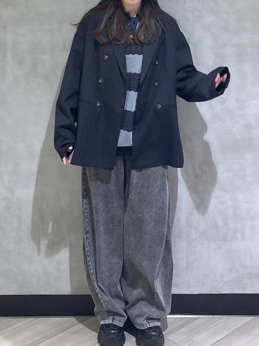 ブラック系のスニーカー、ブラック系のデニムパンツ、ブルー系のテーラードジャケットを着用したレディースの春コーディネートの2枚目の写真