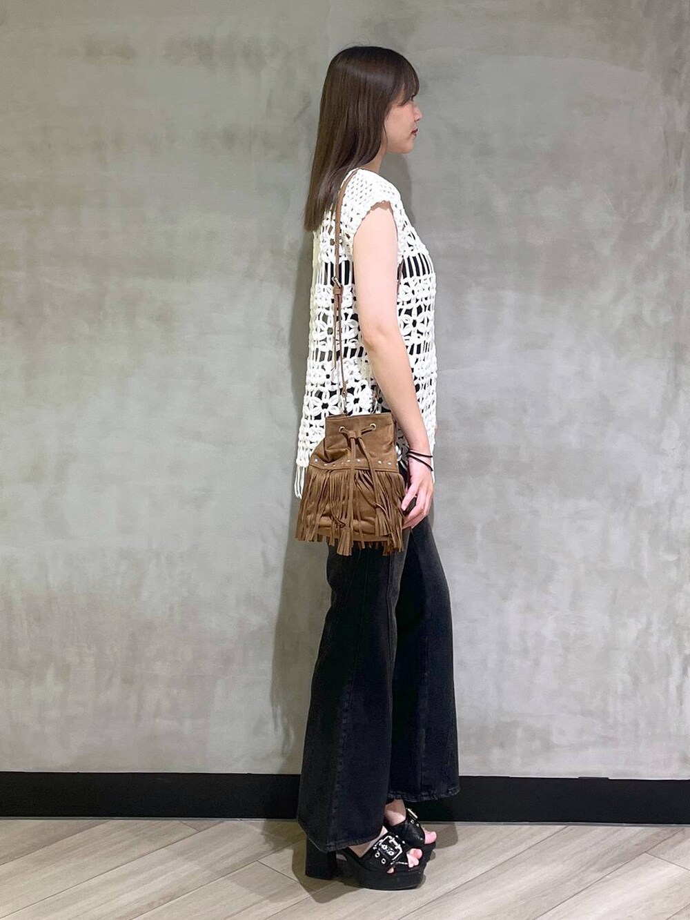 ブラック系のブーツ、ブラック系のデニムパンツ、ホワイト系のベストを着用したレディースの夏コーディネートの7枚目の写真