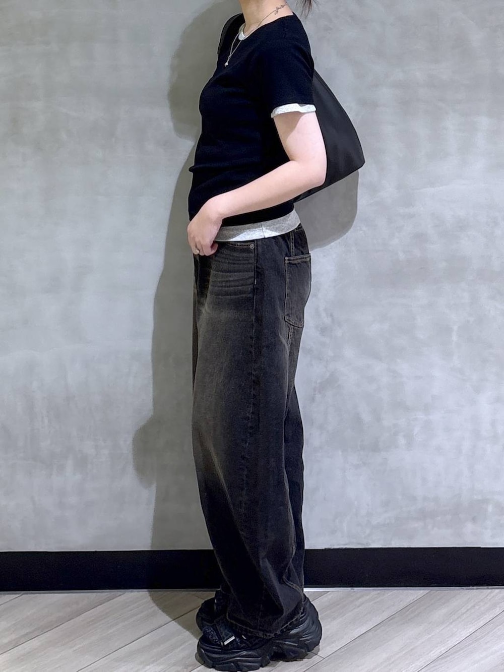 ブラック系のデニムパンツ、ブラック系のサンダル、ホワイト系のTシャツ/カットソーを着用したレディースの春コーディネートの4枚目の写真