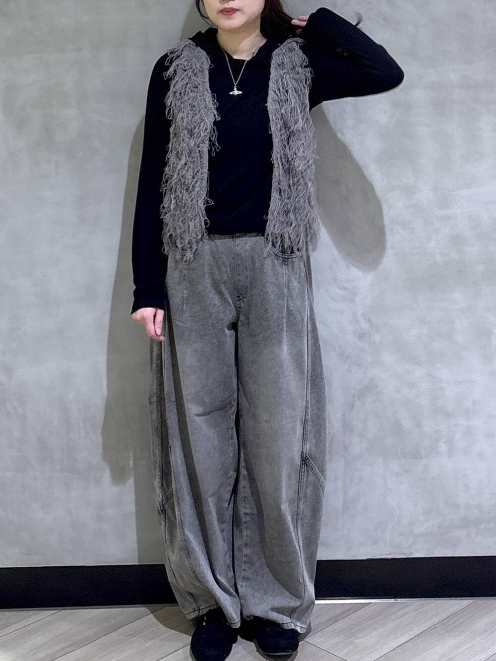 グレー系のベスト、ブラック系のデニムパンツ、ブラック系のTシャツ/カットソーを着用したレディースの春コーディネートの2枚目の写真