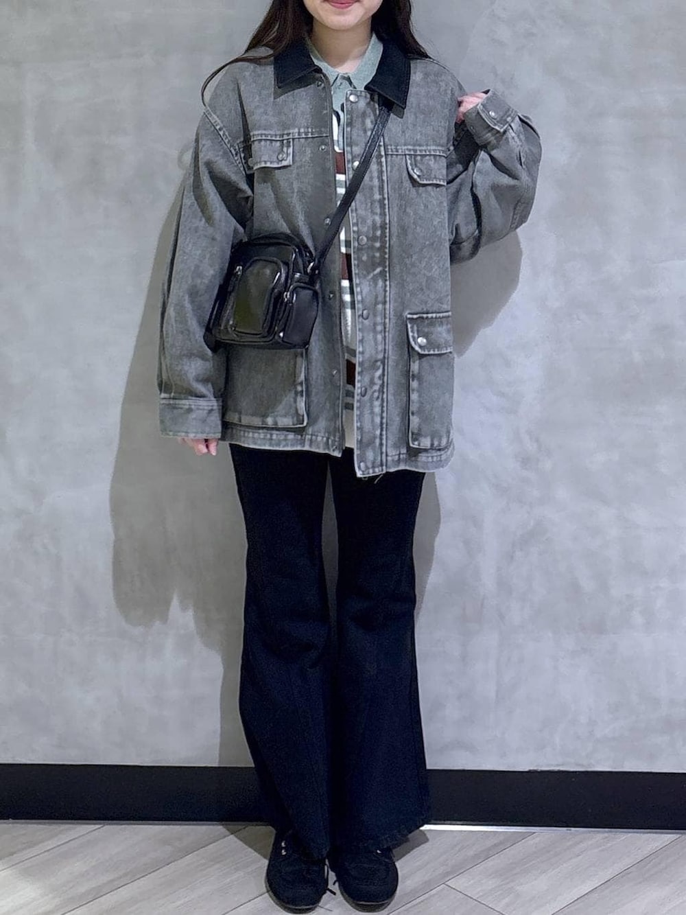 ブラック系のデニムパンツ、ブラック系のモカシン/デッキシューズ、グリーン系のニット/セーターを着用したレディースの春コーディネートの2枚目の写真