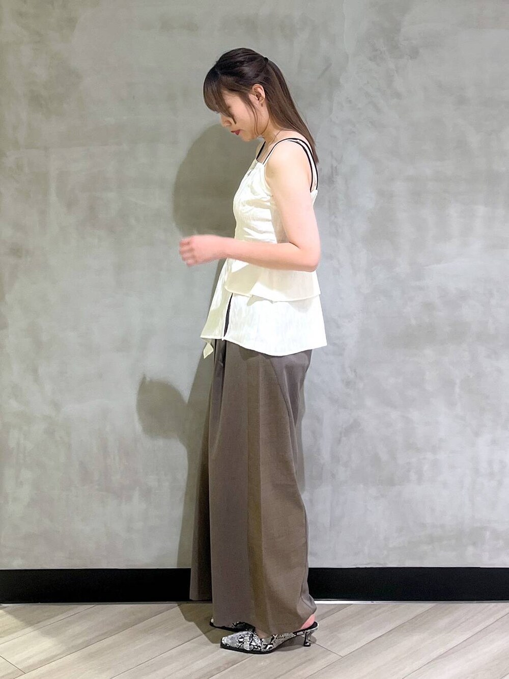 ホワイト系のパンプス、ブラウン系のスラックス、ホワイト系のキャミソールを着用したレディースの夏コーディネートの4枚目の写真