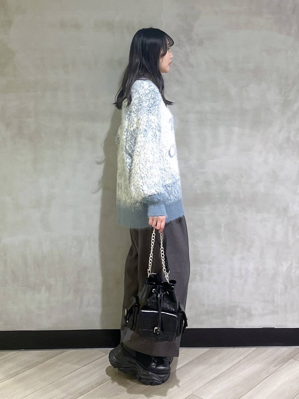 ブラック系のスニーカー、ブルー系のニット/セーター、グレー系のスラックスを着用したレディースの秋コーディネートの7枚目の写真