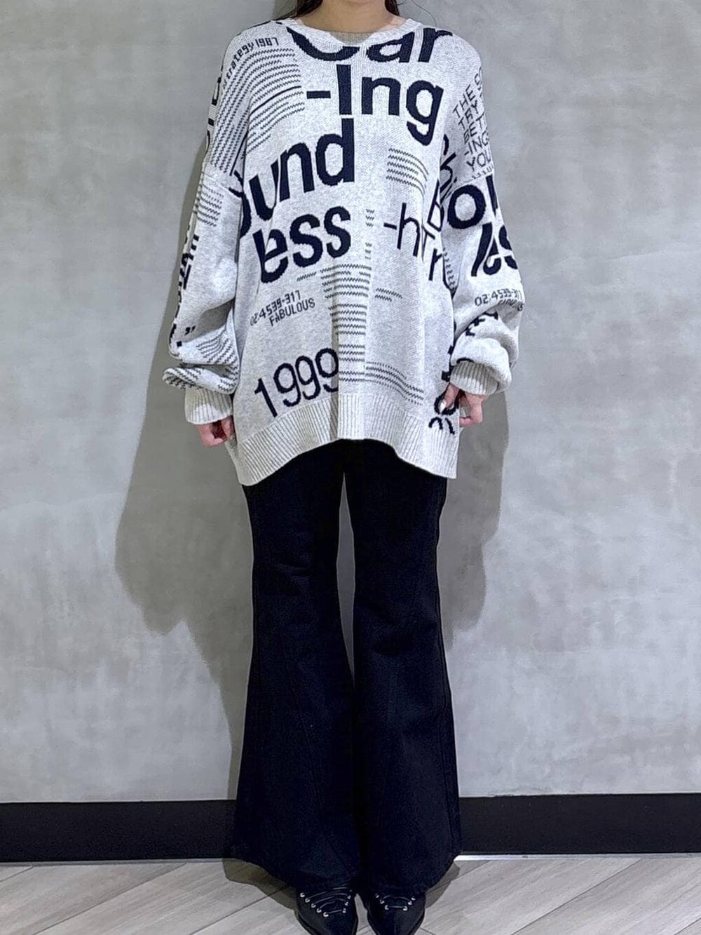 ブルー系のデニムパンツ、ブラック系のサンダル、グレー系のニット/セーターを着用したレディースの冬コーディネートの2枚目の写真