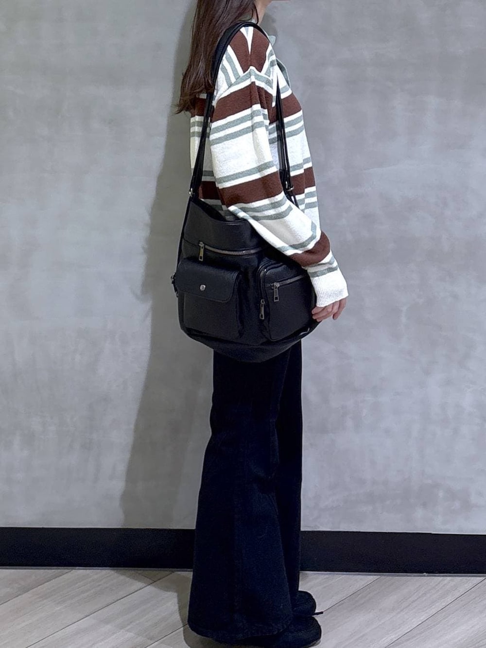 ブラック系のデニムパンツ、ブラック系のモカシン/デッキシューズ、グリーン系のニット/セーターを着用したレディースの春コーディネートの7枚目の写真