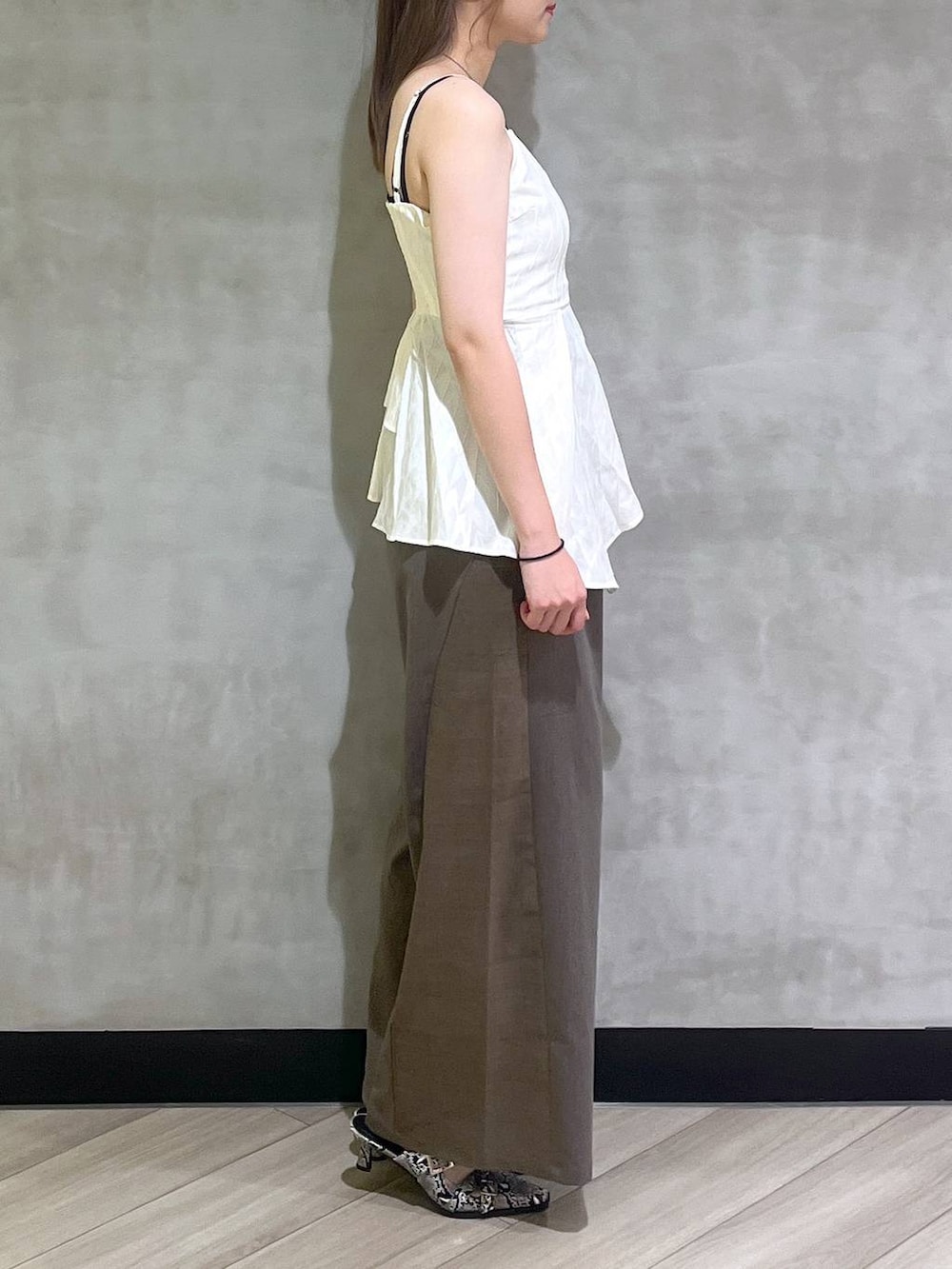 ホワイト系のパンプス、ブラウン系のスラックス、ホワイト系のキャミソールを着用したレディースの夏コーディネートの7枚目の写真