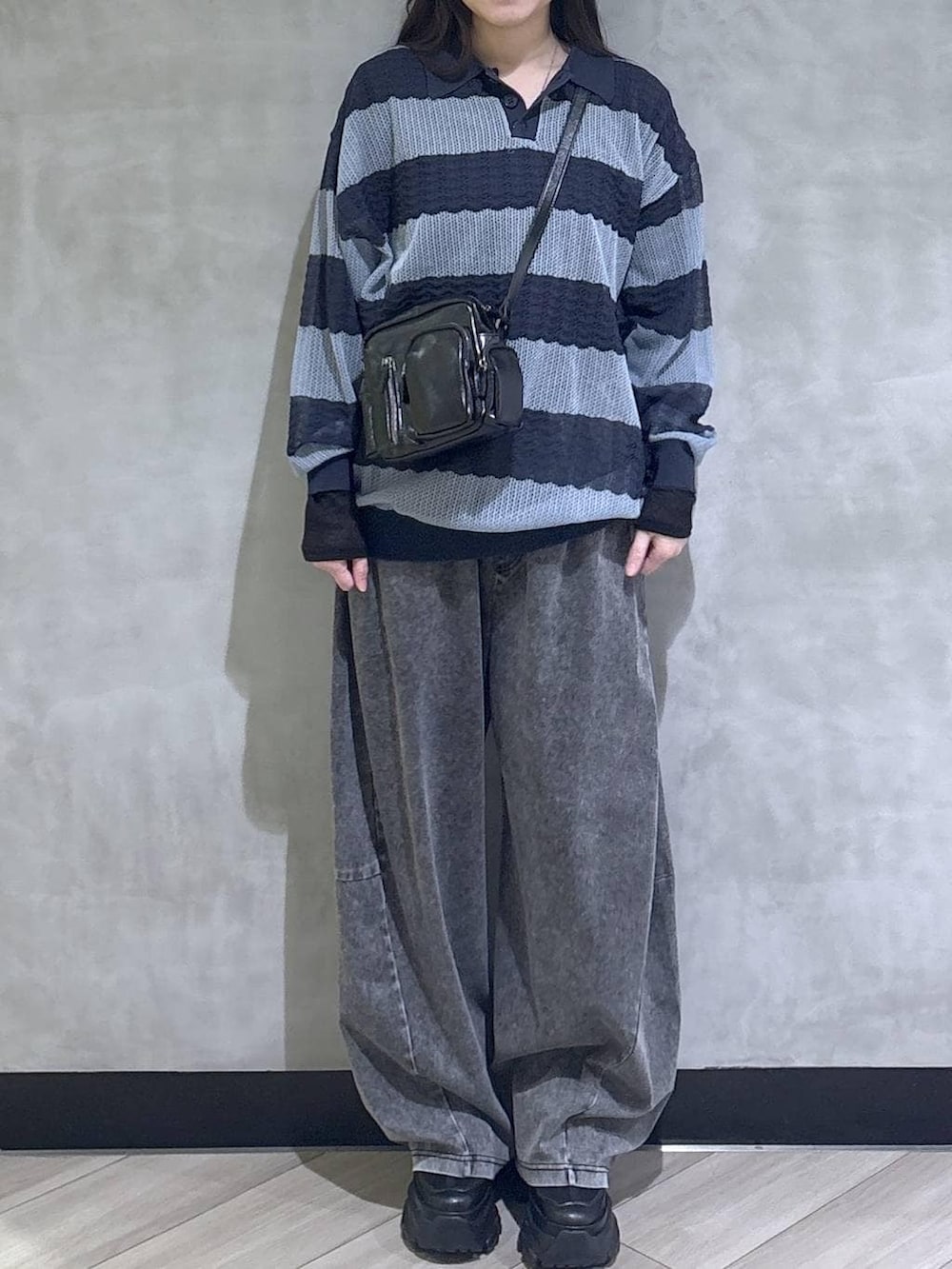 ブラック系のスニーカー、ブラック系のデニムパンツ、ブルー系のポロシャツを着用したレディースの春コーディネートの2枚目の写真