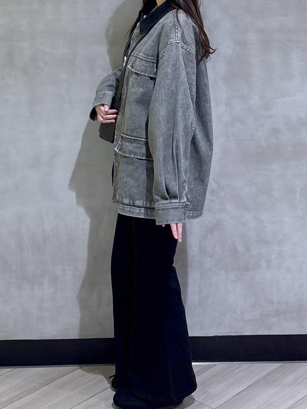 ブラック系のデニムパンツ、ブラック系のモカシン/デッキシューズ、グリーン系のニット/セーターを着用したレディースの春コーディネートの4枚目の写真