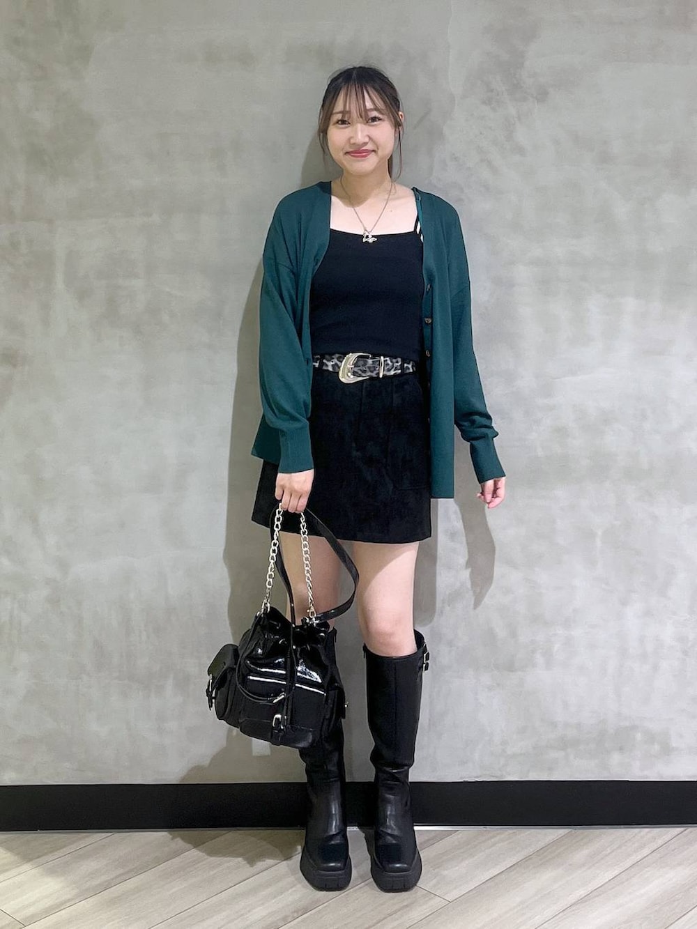 ブラック系のブーツ、ブラック系のスカート、グリーン系のカーディガン/ボレロを着用したレディースの秋コーディネートの2枚目の写真