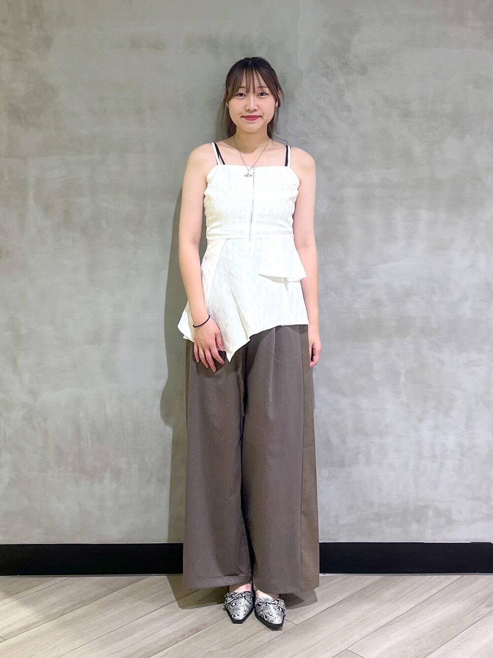 ホワイト系のパンプス、ブラウン系のスラックス、ホワイト系のキャミソールを着用したレディースの夏コーディネートの2枚目の写真