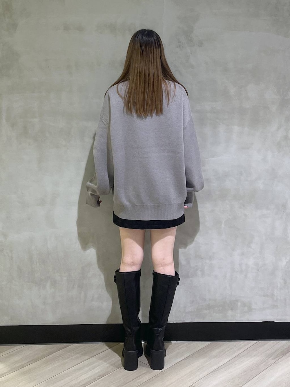 ブラック系のブーツ、ブラック系のスカート、グレー系のニット/セーターを着用したレディースの秋コーディネートの5枚目の写真