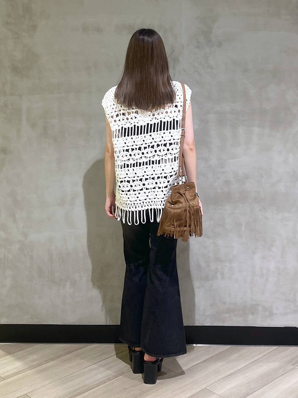 ブラック系のブーツ、ブラック系のデニムパンツ、ホワイト系のベストを着用したレディースの夏コーディネートの5枚目の写真