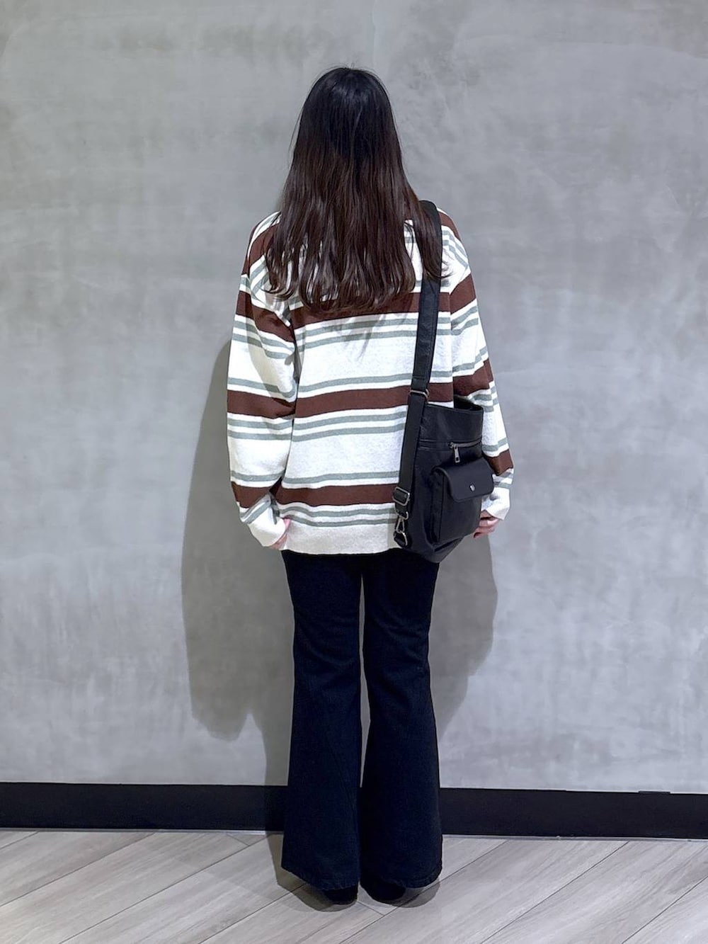 ブラック系のデニムパンツ、ブラック系のモカシン/デッキシューズ、グリーン系のニット/セーターを着用したレディースの春コーディネートの5枚目の写真