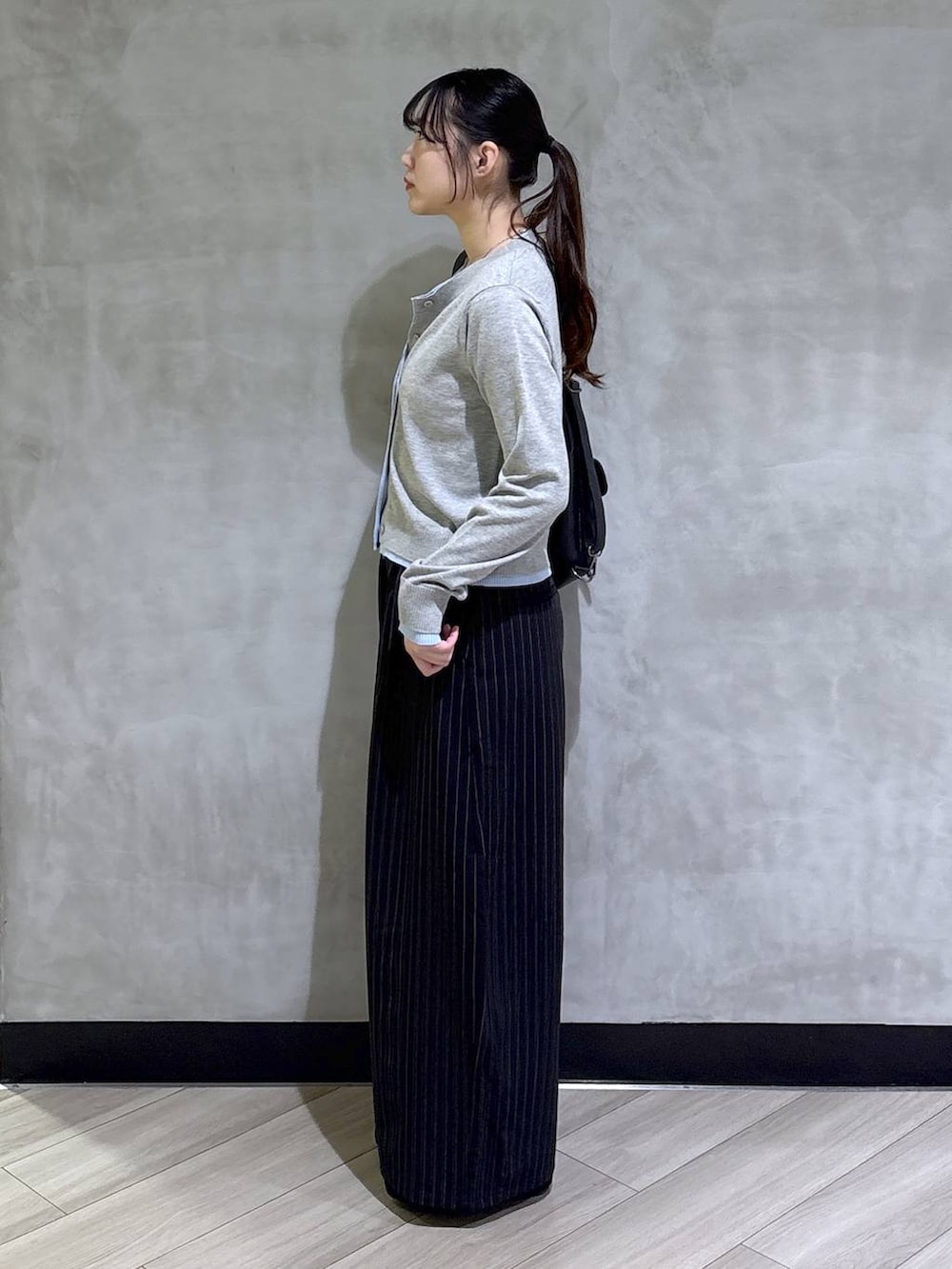 ブラック系のスラックス、グレー系のカーディガン/ボレロ、ブラック系のモカシン/デッキシューズを着用したレディースの春コーディネートの7枚目の写真