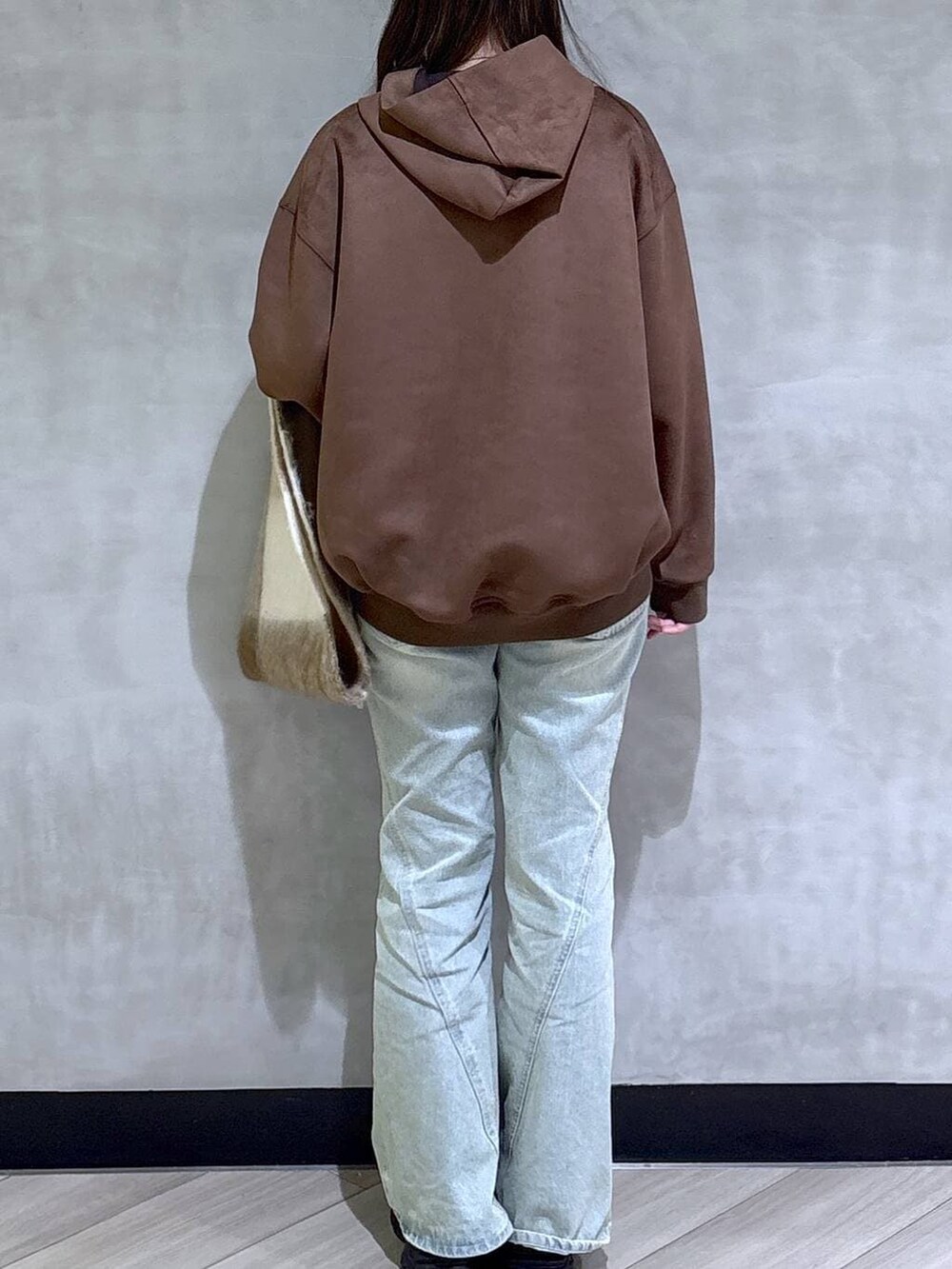 ブルー系のデニムパンツ、ブラック系のパーカー、ブラック系のローファーを着用したレディースの冬コーディネートの6枚目の写真