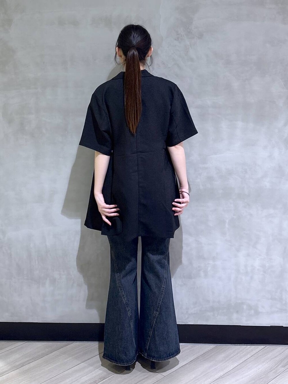 ブルー系のデニムパンツ、ブラック系のサンダル、ブラック系のテーラードジャケットを着用したレディースの春コーディネートの5枚目の写真