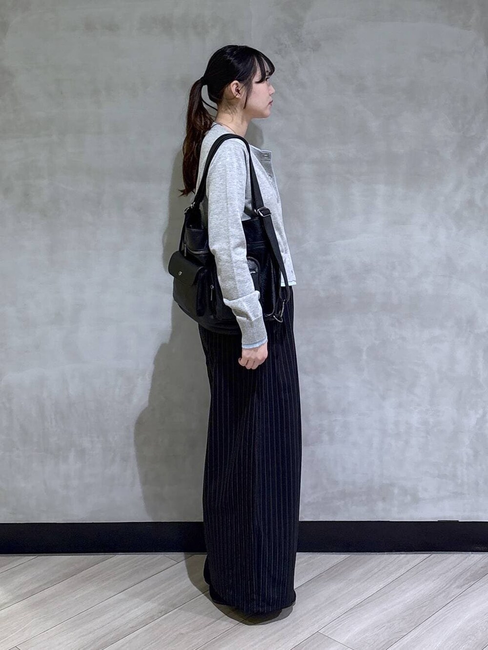 ブラック系のスラックス、グレー系のカーディガン/ボレロ、ブラック系のモカシン/デッキシューズを着用したレディースの春コーディネートの3枚目の写真