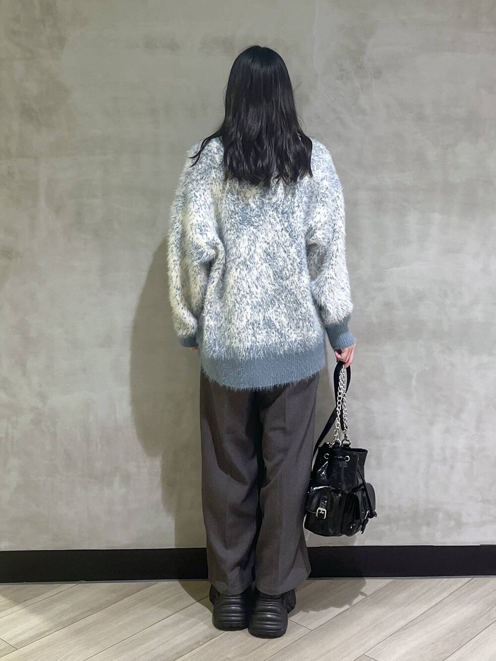 ブラック系のスニーカー、ブルー系のニット/セーター、グレー系のスラックスを着用したレディースの秋コーディネートの5枚目の写真